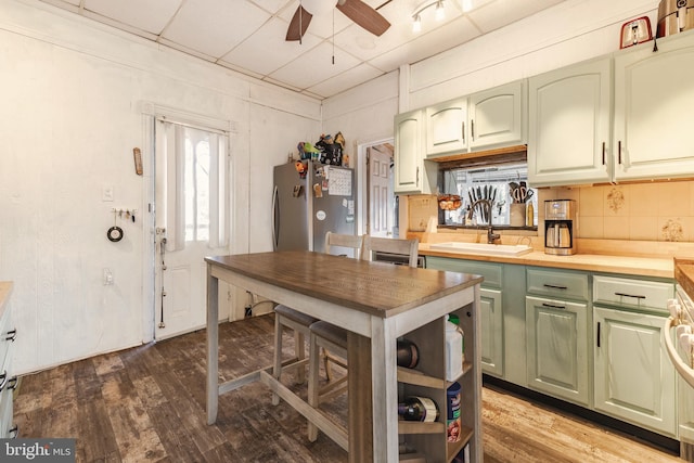 kitchen featuring tasteful backsplash, hardwood / wood-style floors, stainless steel refrigerator, ceiling fan, and sink