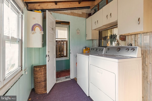 laundry room with washer and clothes dryer, wood walls, a wealth of natural light, and cabinets