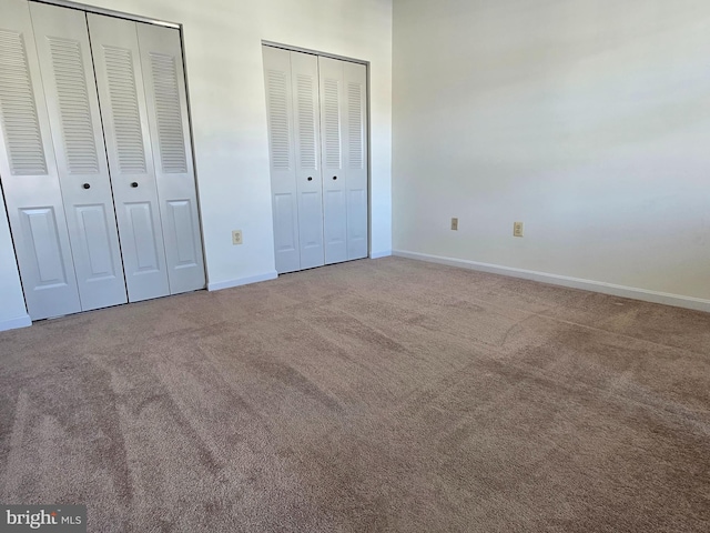 unfurnished bedroom featuring carpet flooring and multiple closets