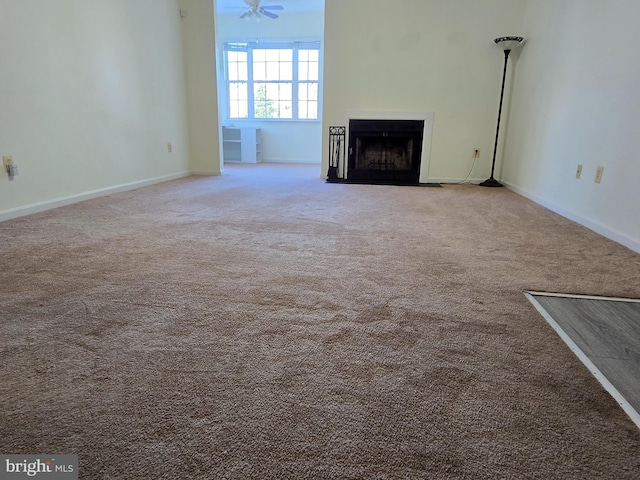 unfurnished living room with ceiling fan and carpet