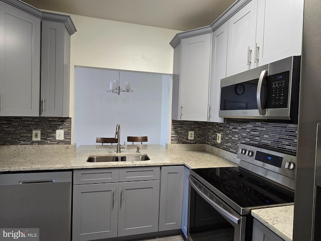 kitchen with a chandelier, stainless steel appliances, gray cabinets, backsplash, and sink