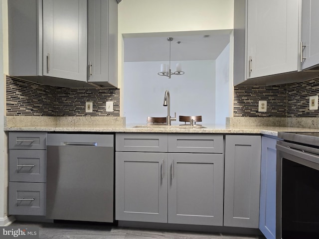 kitchen featuring stainless steel appliances, pendant lighting, tasteful backsplash, and sink