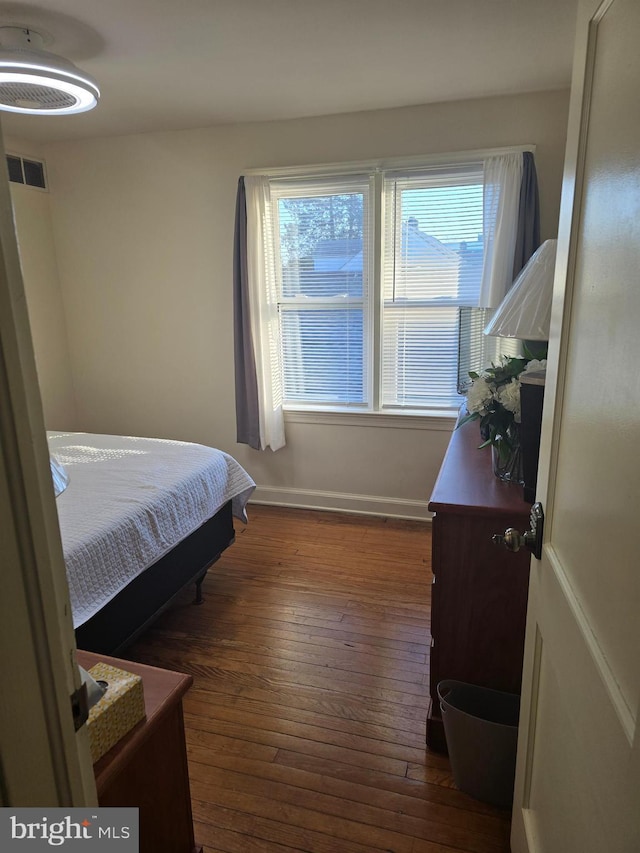 bedroom with dark wood-type flooring and multiple windows