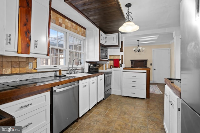 kitchen with a chandelier, appliances with stainless steel finishes, hanging light fixtures, white cabinets, and sink