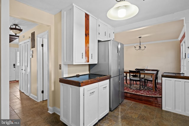 kitchen featuring stainless steel refrigerator, white cabinets, and ornamental molding