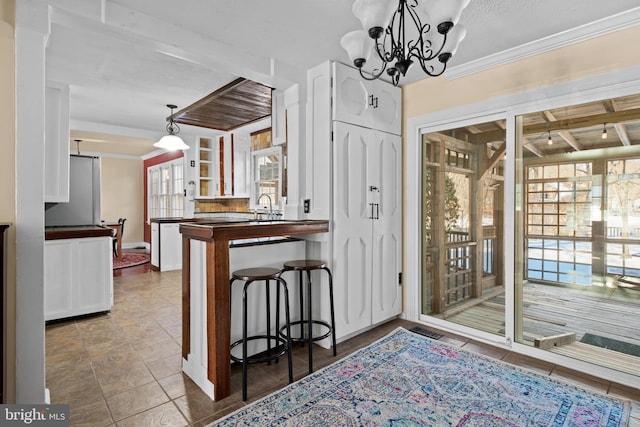 kitchen with white cabinets, ornamental molding, and pendant lighting