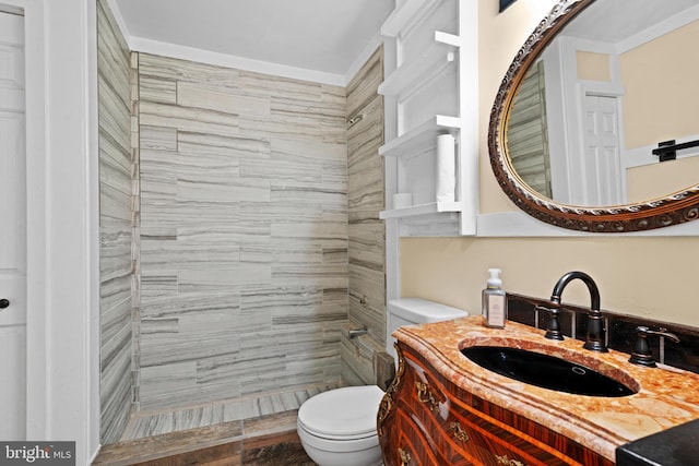 bathroom with tiled shower, vanity, and toilet