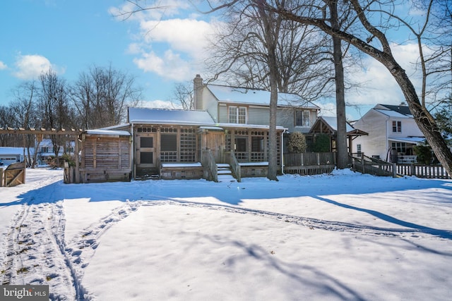 snow covered back of property with covered porch