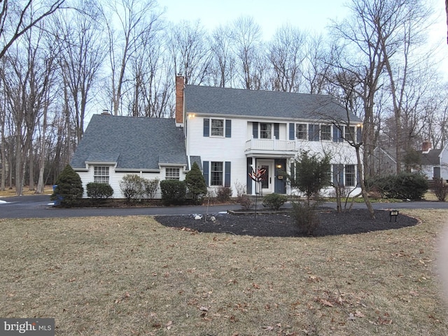 colonial-style house featuring a front lawn