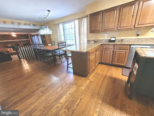 kitchen featuring an inviting chandelier, a kitchen bar, kitchen peninsula, light stone countertops, and light hardwood / wood-style flooring