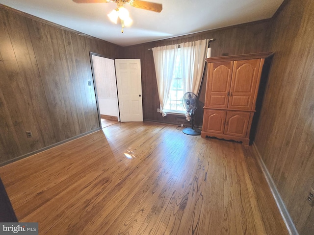 empty room with ceiling fan, wooden walls, and hardwood / wood-style floors