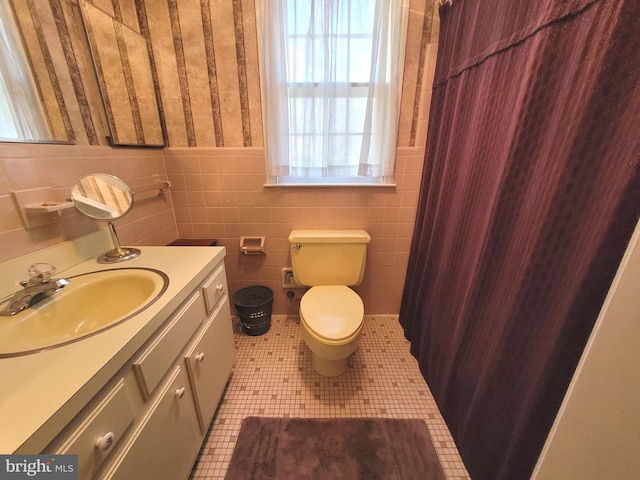 bathroom with toilet, vanity, tile walls, and tile patterned flooring