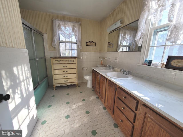 full bathroom featuring toilet, bath / shower combo with glass door, tile walls, tile patterned floors, and vanity