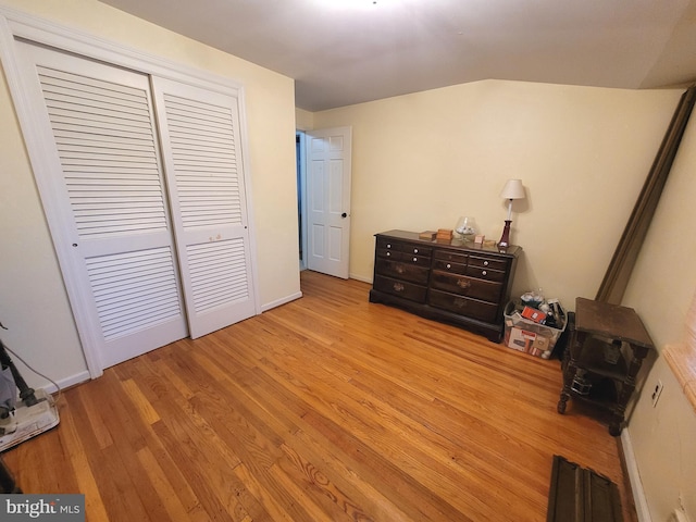 bedroom featuring light wood-type flooring, a closet, and vaulted ceiling