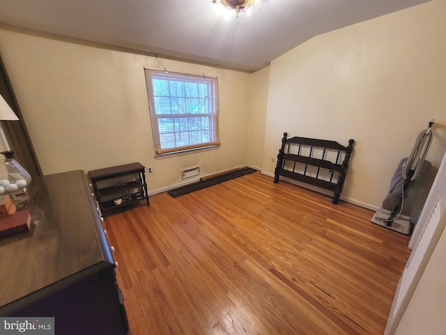 unfurnished bedroom with vaulted ceiling, hardwood / wood-style flooring, and a wall mounted air conditioner