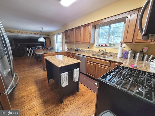 kitchen featuring light hardwood / wood-style floors, appliances with stainless steel finishes, sink, pendant lighting, and a center island