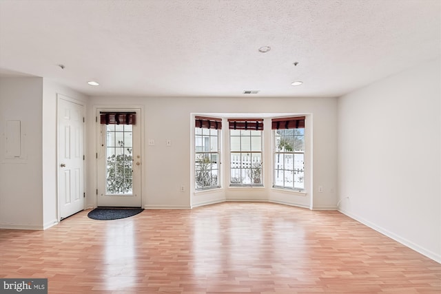 unfurnished room with a textured ceiling and light hardwood / wood-style flooring