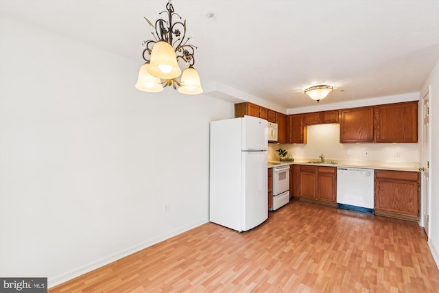 kitchen with white appliances, light hardwood / wood-style flooring, pendant lighting, a notable chandelier, and sink