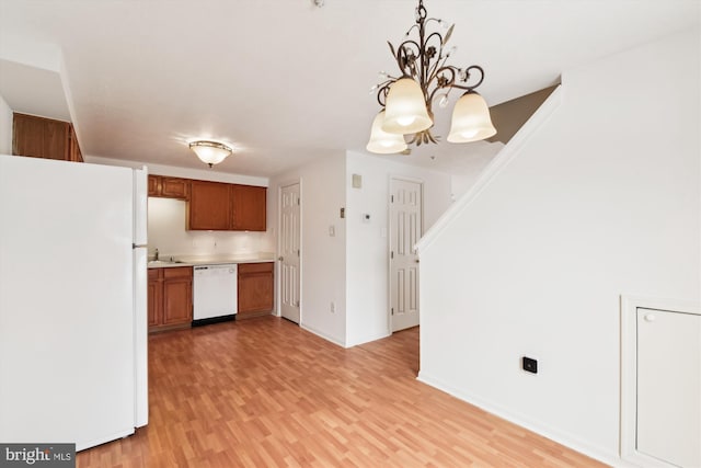 kitchen featuring white appliances, hanging light fixtures, light hardwood / wood-style flooring, and a chandelier