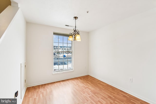 spare room featuring hardwood / wood-style flooring and an inviting chandelier