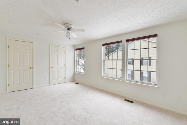 unfurnished room featuring a textured ceiling, carpet floors, and ceiling fan