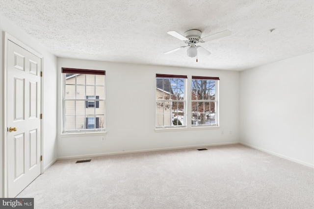 empty room featuring a textured ceiling, ceiling fan, and light carpet