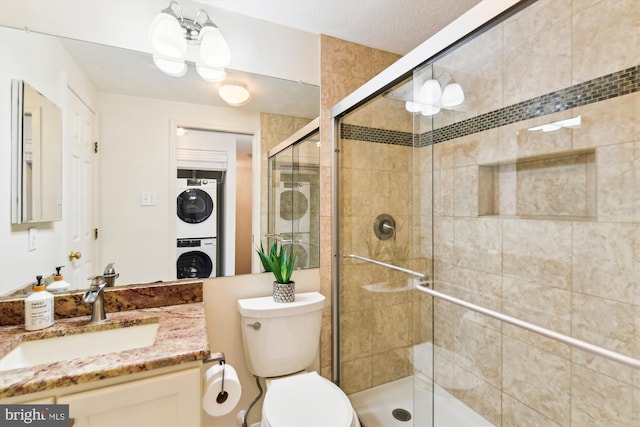 bathroom featuring toilet, stacked washer and clothes dryer, vanity, and a shower with door