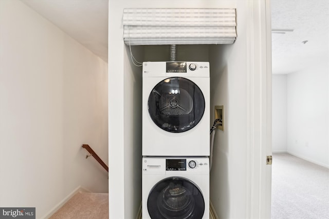 laundry area with carpet flooring, a textured ceiling, and stacked washer and clothes dryer