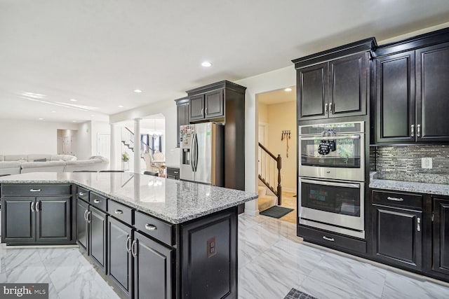 kitchen with ornate columns, decorative backsplash, stainless steel appliances, and light stone counters