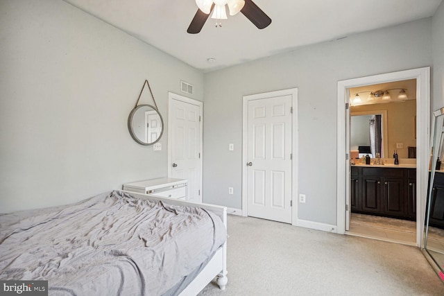 bedroom featuring ceiling fan, light colored carpet, sink, and ensuite bath