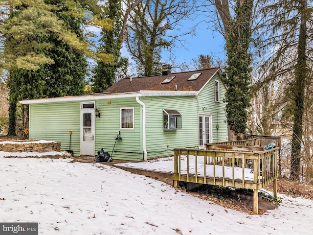 snow covered house featuring a wooden deck