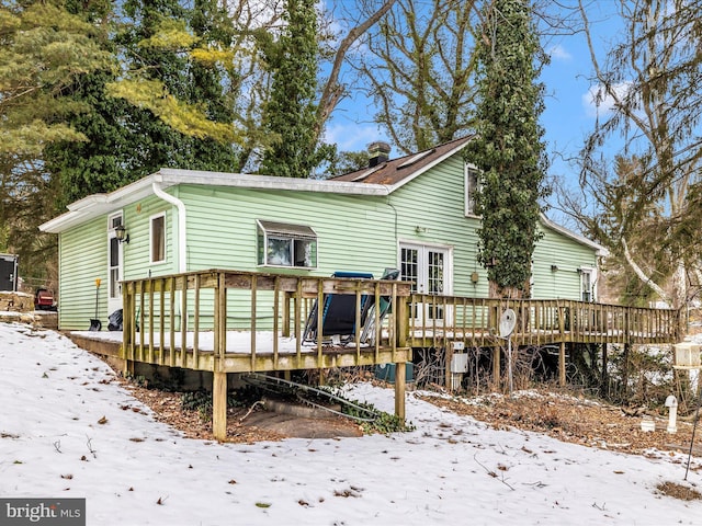 snow covered house featuring a wooden deck and french doors