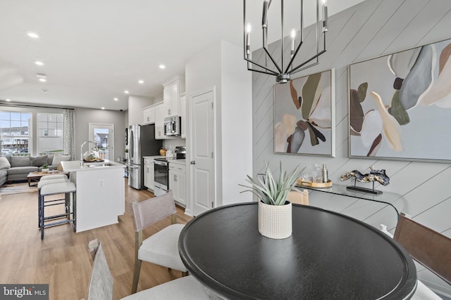 dining space with a chandelier, sink, and light hardwood / wood-style flooring