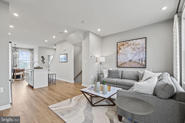 living room with light hardwood / wood-style floors and a notable chandelier