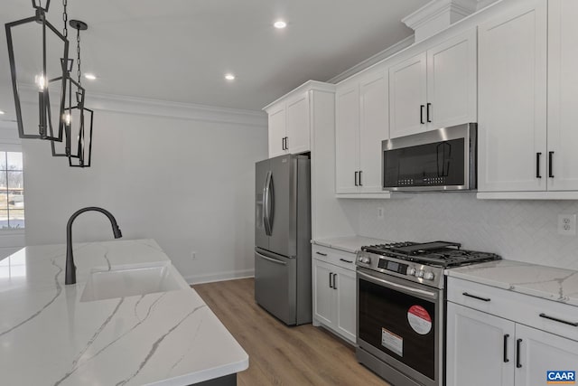 kitchen featuring white cabinets, decorative light fixtures, stainless steel appliances, and light stone counters