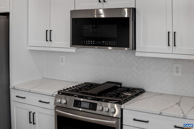 kitchen with white cabinets, appliances with stainless steel finishes, backsplash, and light stone counters