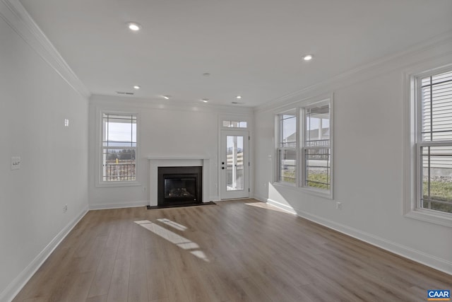 unfurnished living room featuring a healthy amount of sunlight, ornamental molding, and light hardwood / wood-style flooring