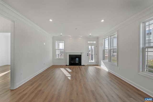 unfurnished living room featuring light hardwood / wood-style floors, crown molding, and a wealth of natural light