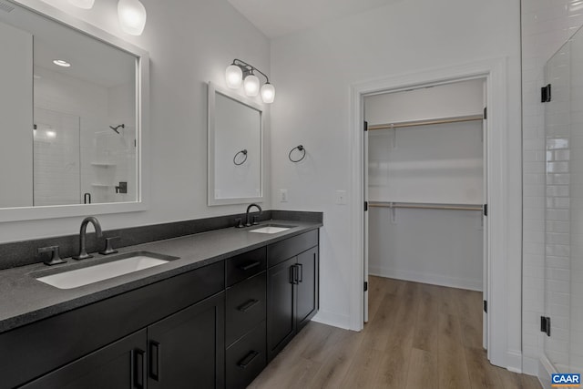 bathroom featuring a shower with shower door, wood-type flooring, and vanity