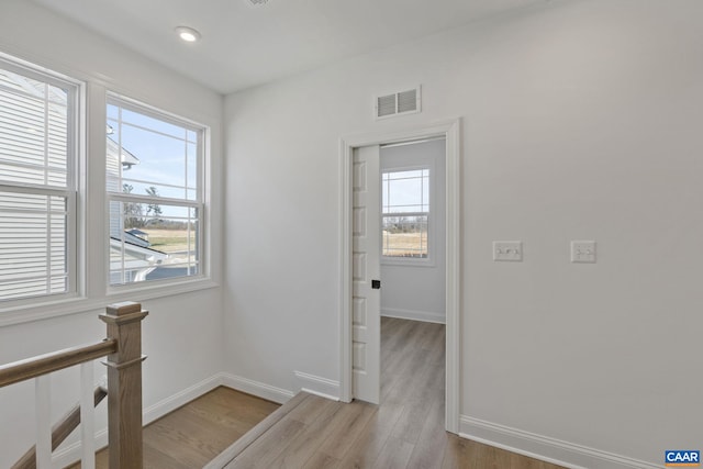 hall featuring plenty of natural light and light hardwood / wood-style floors