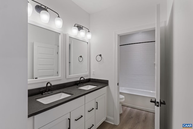 full bathroom featuring hardwood / wood-style floors, vanity, tiled shower / bath combo, and toilet