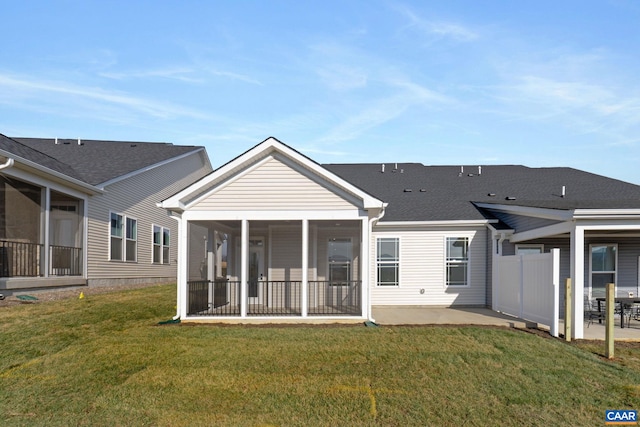 rear view of property with a yard, a patio, and a sunroom