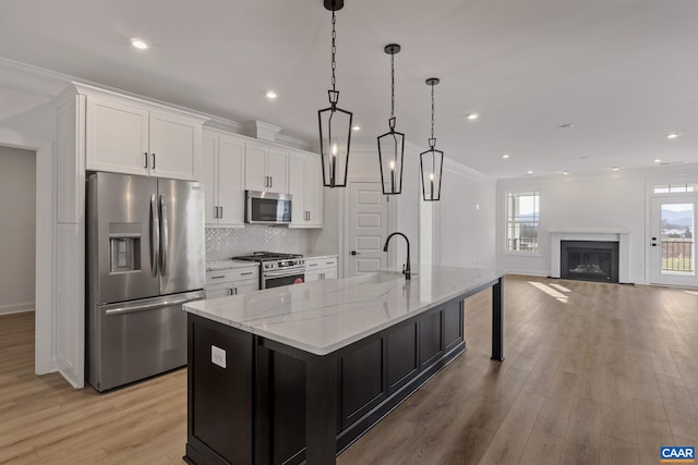 kitchen featuring light stone counters, stainless steel appliances, sink, white cabinets, and a large island