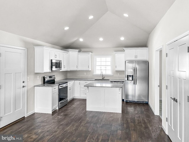 kitchen with stainless steel appliances, sink, white cabinets, a center island, and lofted ceiling