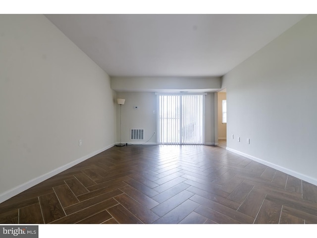 spare room featuring dark parquet flooring