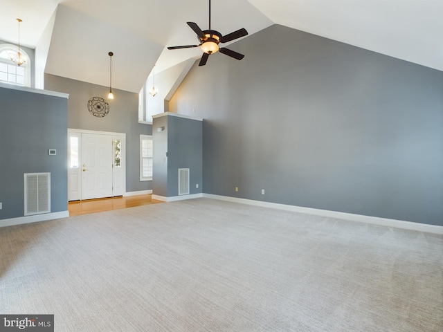 unfurnished living room with ceiling fan, a wealth of natural light, carpet flooring, and high vaulted ceiling