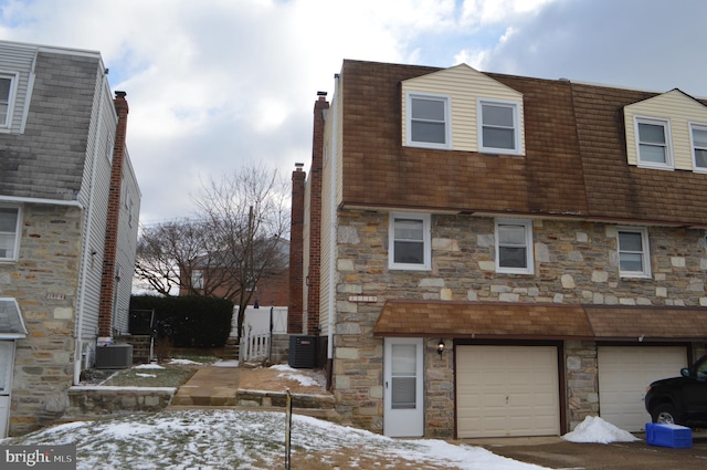 view of snow covered exterior with central air condition unit and a garage