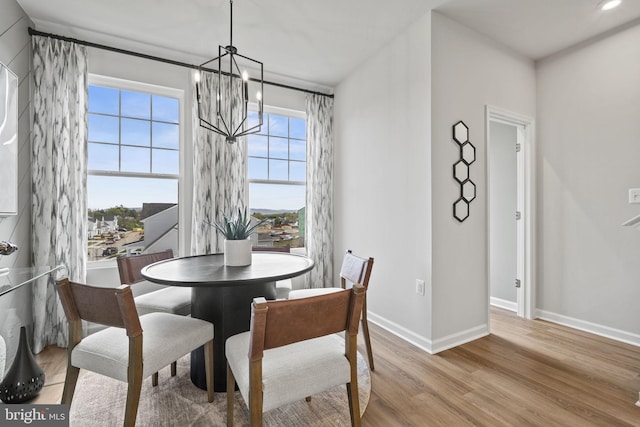 dining space with light hardwood / wood-style floors and an inviting chandelier