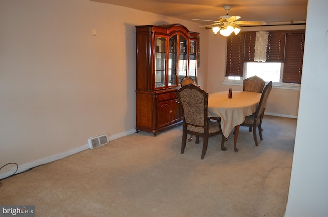 dining space featuring ceiling fan and light colored carpet