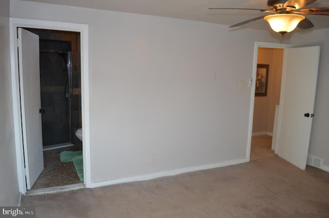 unfurnished bedroom featuring connected bathroom, a closet, light carpet, ceiling fan, and a walk in closet